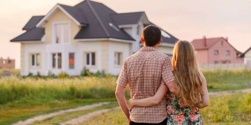 Couple standing in from of their new farmhouse.