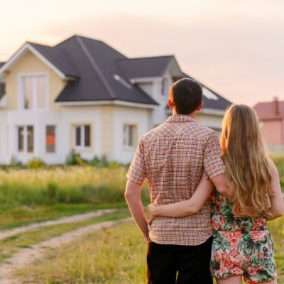 Couple standing in front of their new home.