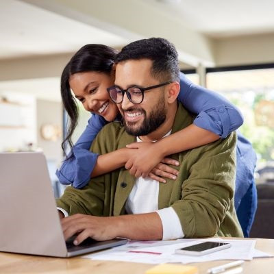 Couple looking over their wedding finances on their laptop.